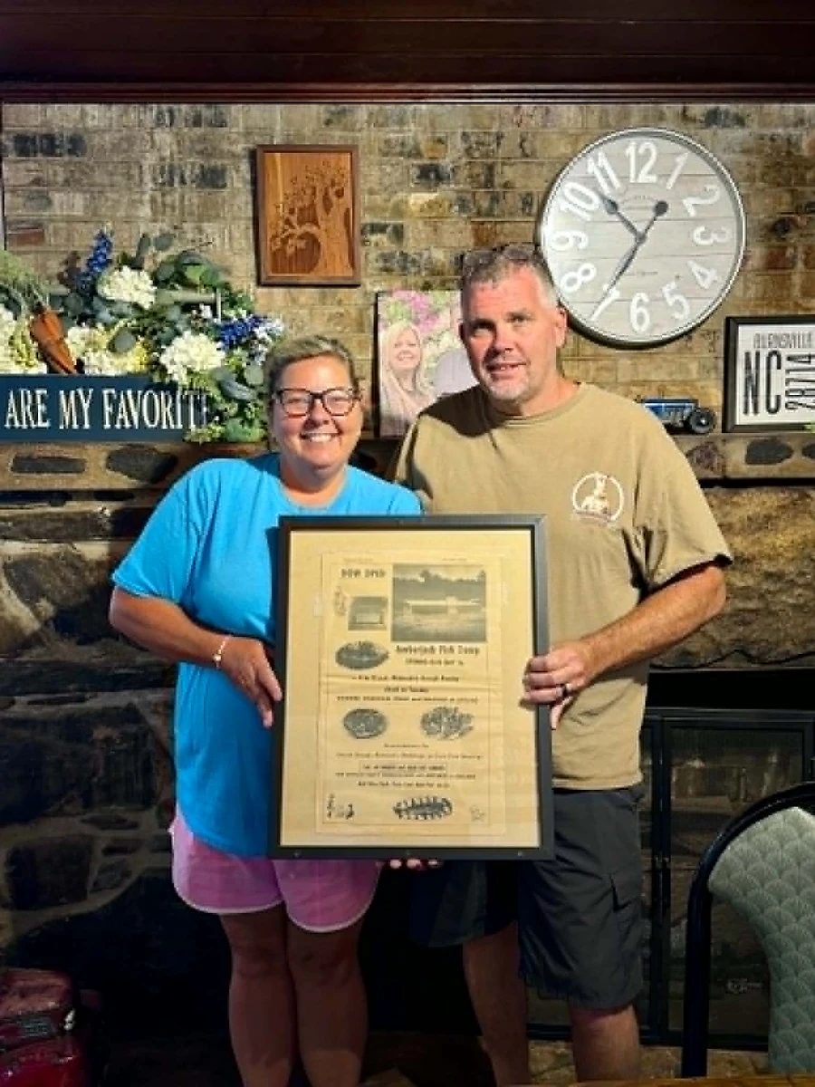 Laura Boyd and her husband showing a news article about the original Amber Jack restaurant